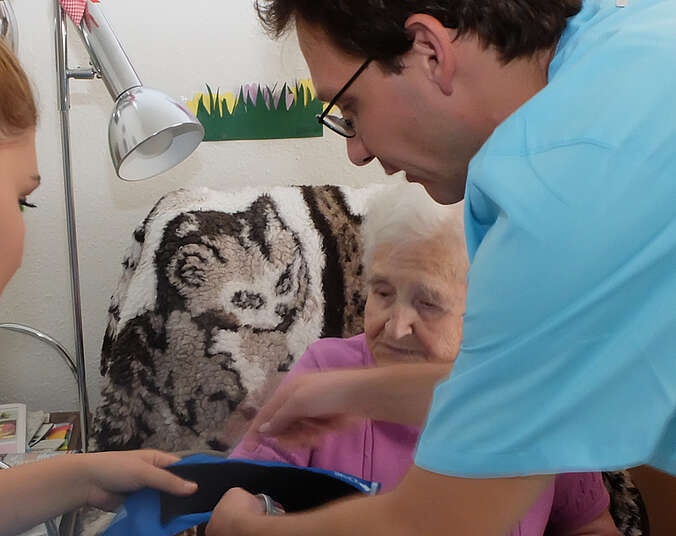 Mann erklärt Blutdruckmessen bei Seniorin