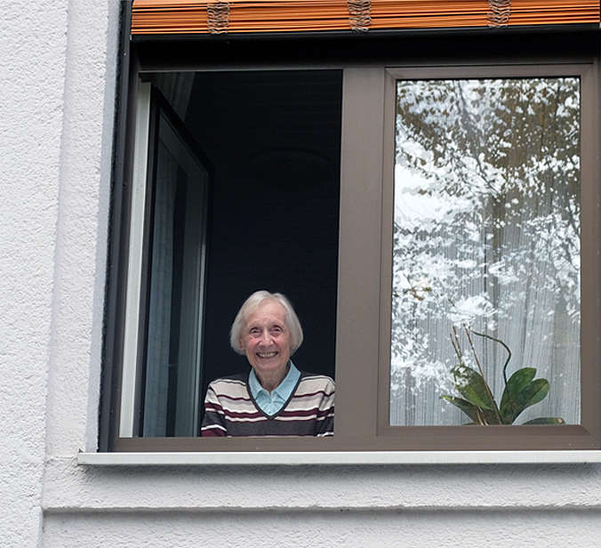 Seniorin schaut aus Fenster